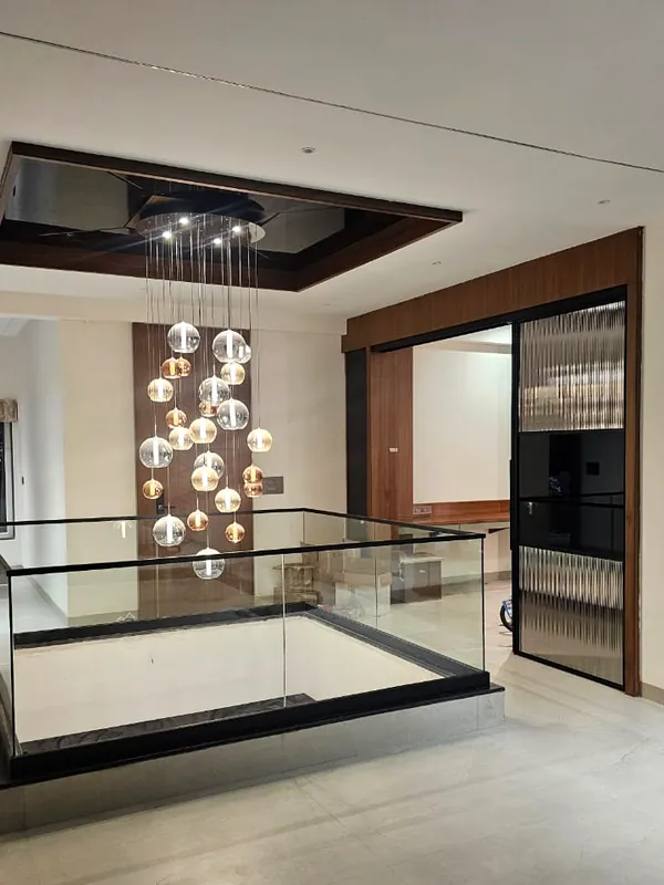 A double-height void with a glass balustrade and a cluster of pendants.