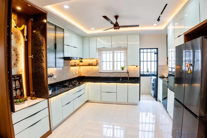 A white kitchen with a carved pooja unit.